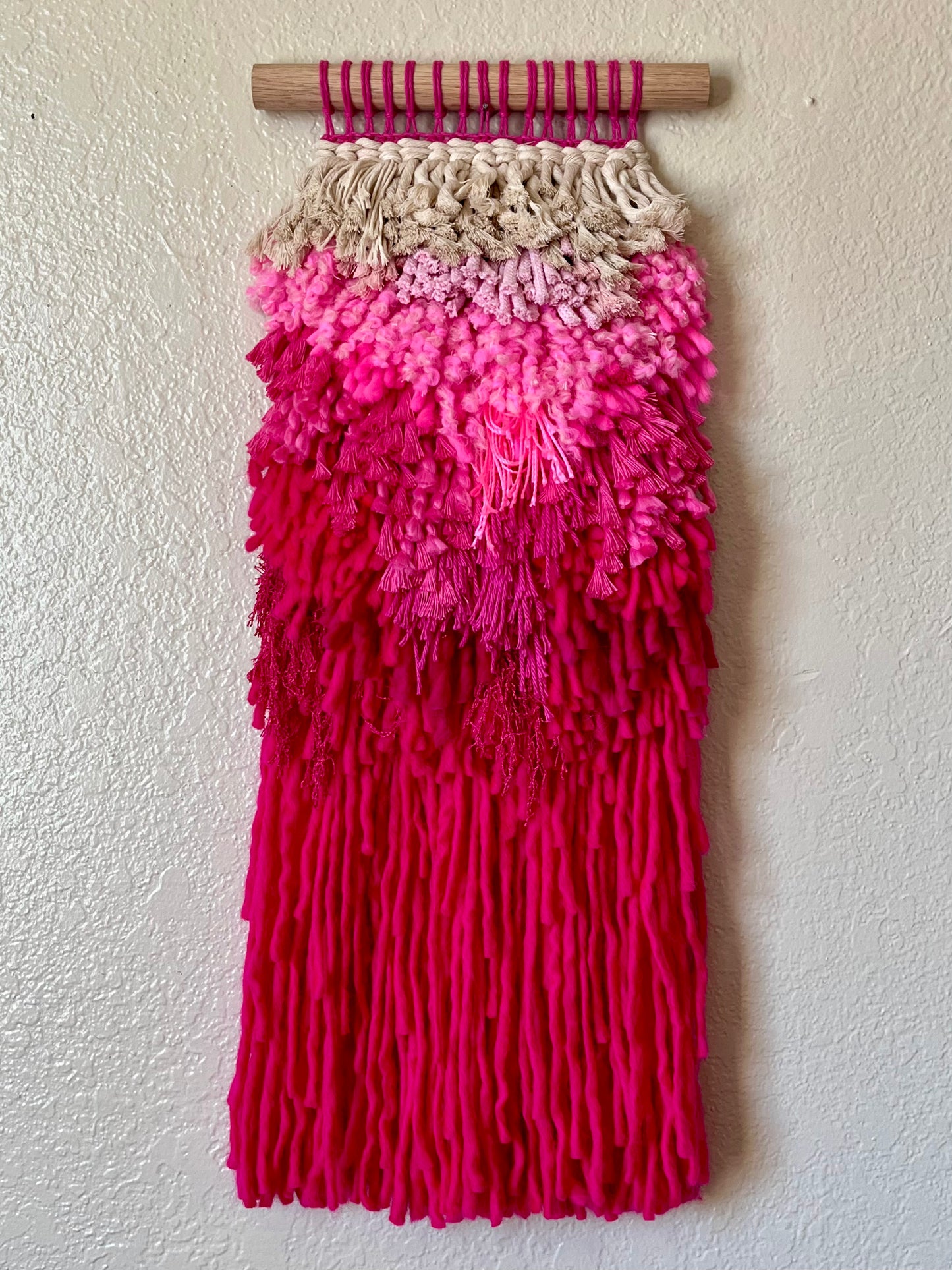 Pink ombre wall art with textured layers on a white wall